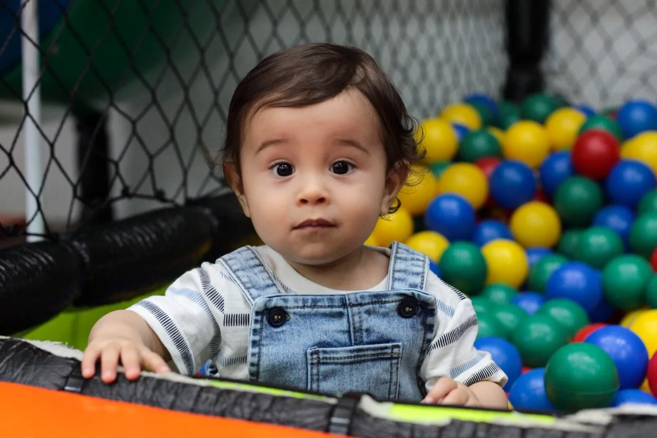 Menino aniversariante na piscina de bolinhas coloridas.